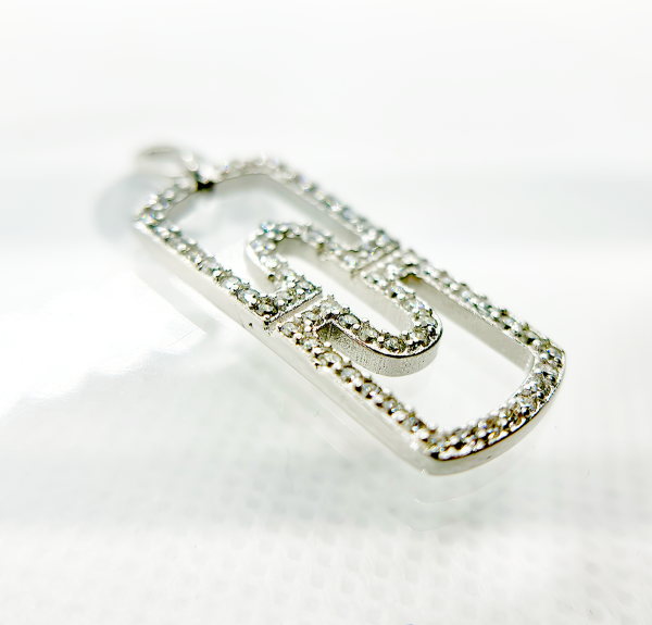 A diamond-encrusted silver pendant in the shape of a paperclip