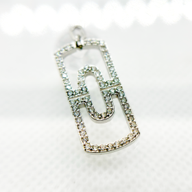 A diamond-encrusted silver pendant in the shape of a paperclip