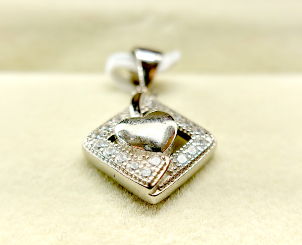 A silver heart-shaped pendant with a diamond-encrusted frame