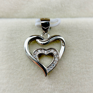 A heart-shaped silver pendant with a smaller heart inside, both adorned with small diamonds