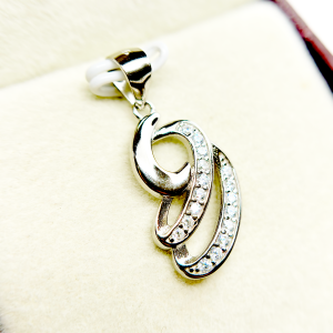 A silver pendant with a swirling design and embedded with small diamonds