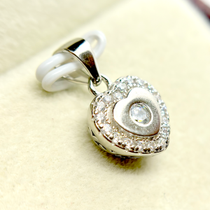 A heart-shaped pendant with a diamond in the center surrounded by smaller diamonds