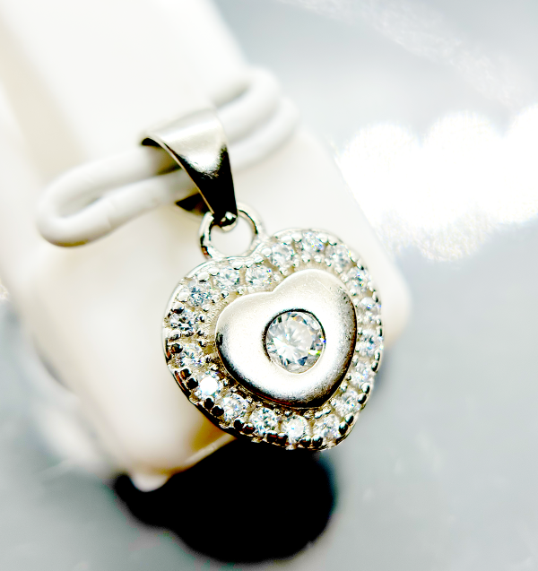 A heart-shaped pendant with a diamond in the center surrounded by smaller diamonds