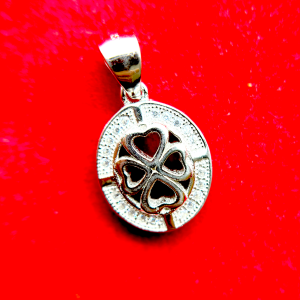 Close-up of a silver pendant with a heart-shaped cutout and a clover design, encrusted with small diamonds