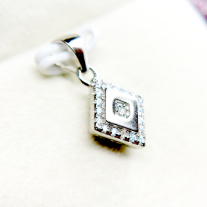 A square-shaped pendant with a concentric diamond design, surrounded by smaller diamonds