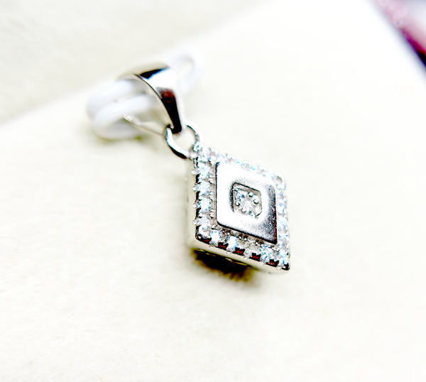 A square-shaped pendant with a concentric diamond design, surrounded by smaller diamonds