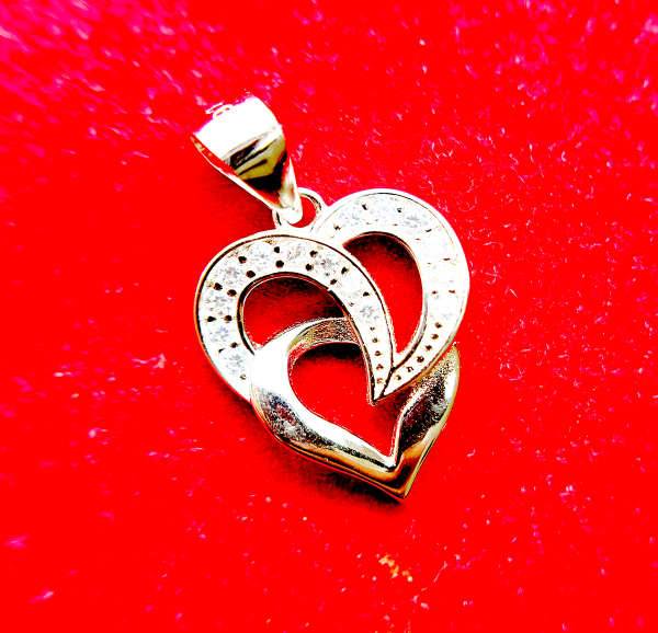 A silver heart-shaped pendant with an intertwined design and small diamond