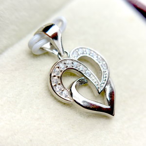 A silver heart-shaped pendant with an intertwined design and small diamond