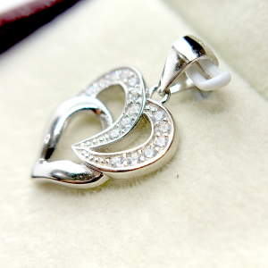 A silver heart-shaped pendant with an intertwined design and small diamond