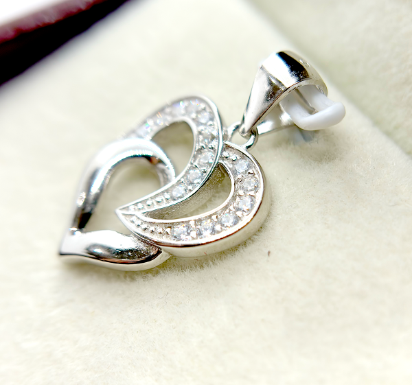 A silver heart-shaped pendant with an intertwined design and small diamond