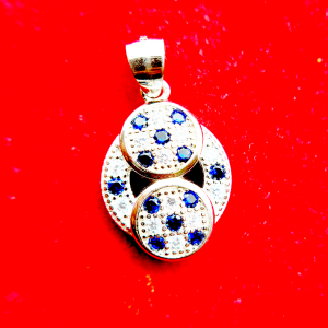Silver pendant with three interconnected circular elements, each set with blue gemstones and surrounded by smaller diamonds