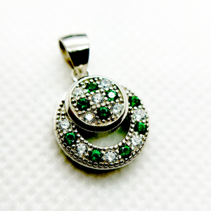 A circular pendant with green and clear gemstones set in a silver