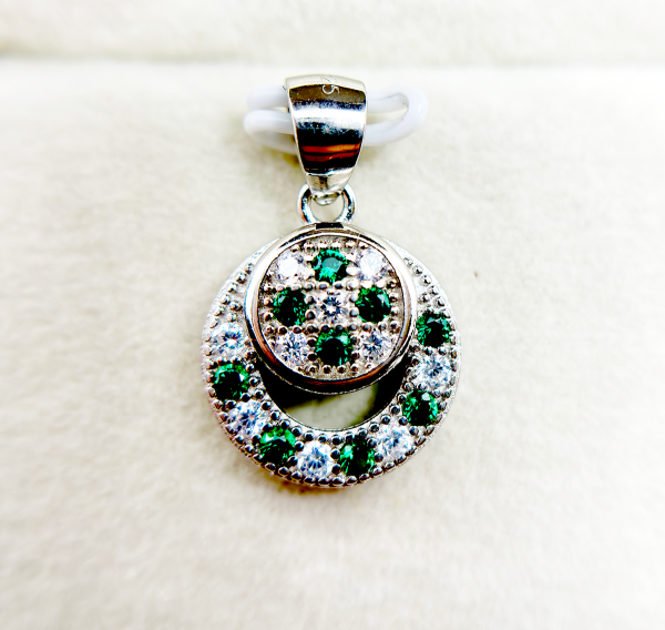 A circular pendant with green and clear gemstones set in a silver